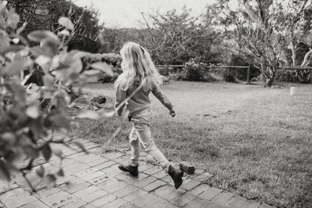 Black and white photo of a girl running in a garden