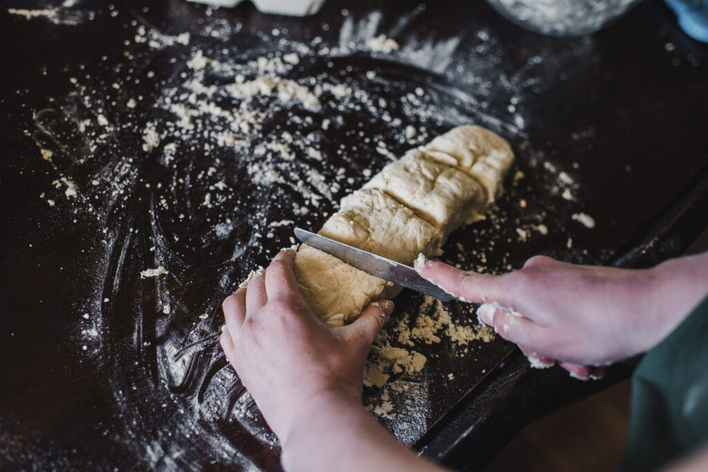 Child cutting scones on a floured board