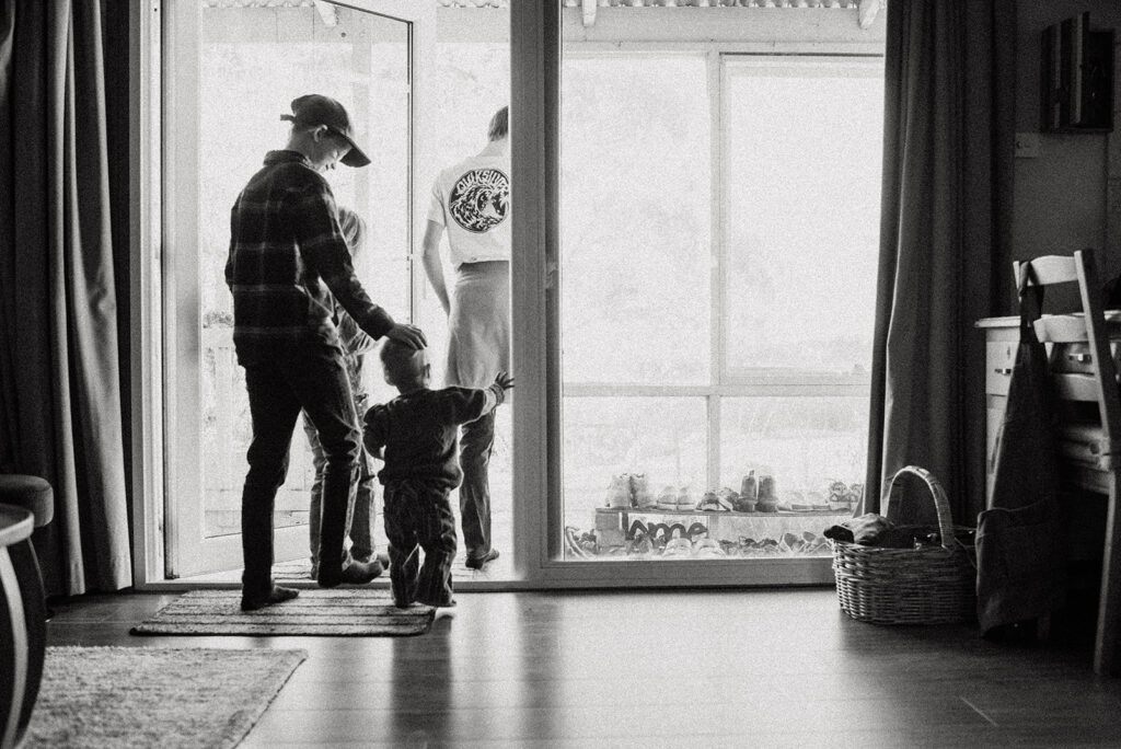 Black and white photo of children walking out from a door to the garden