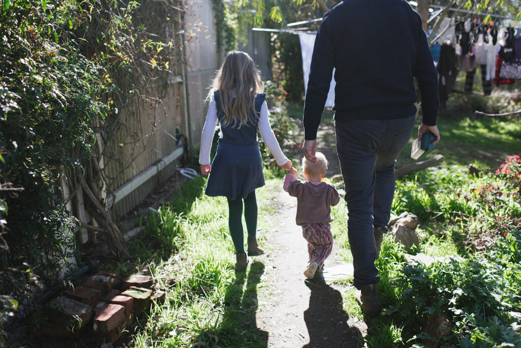 Father and daughter walking holding a baby's hands