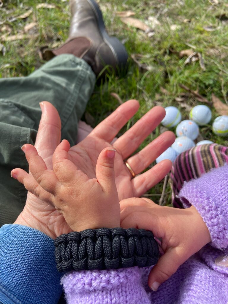 Baby's hand on mother's hand sitting outside